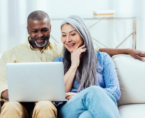 Two people sat by laptop reading fundraising how to guides.