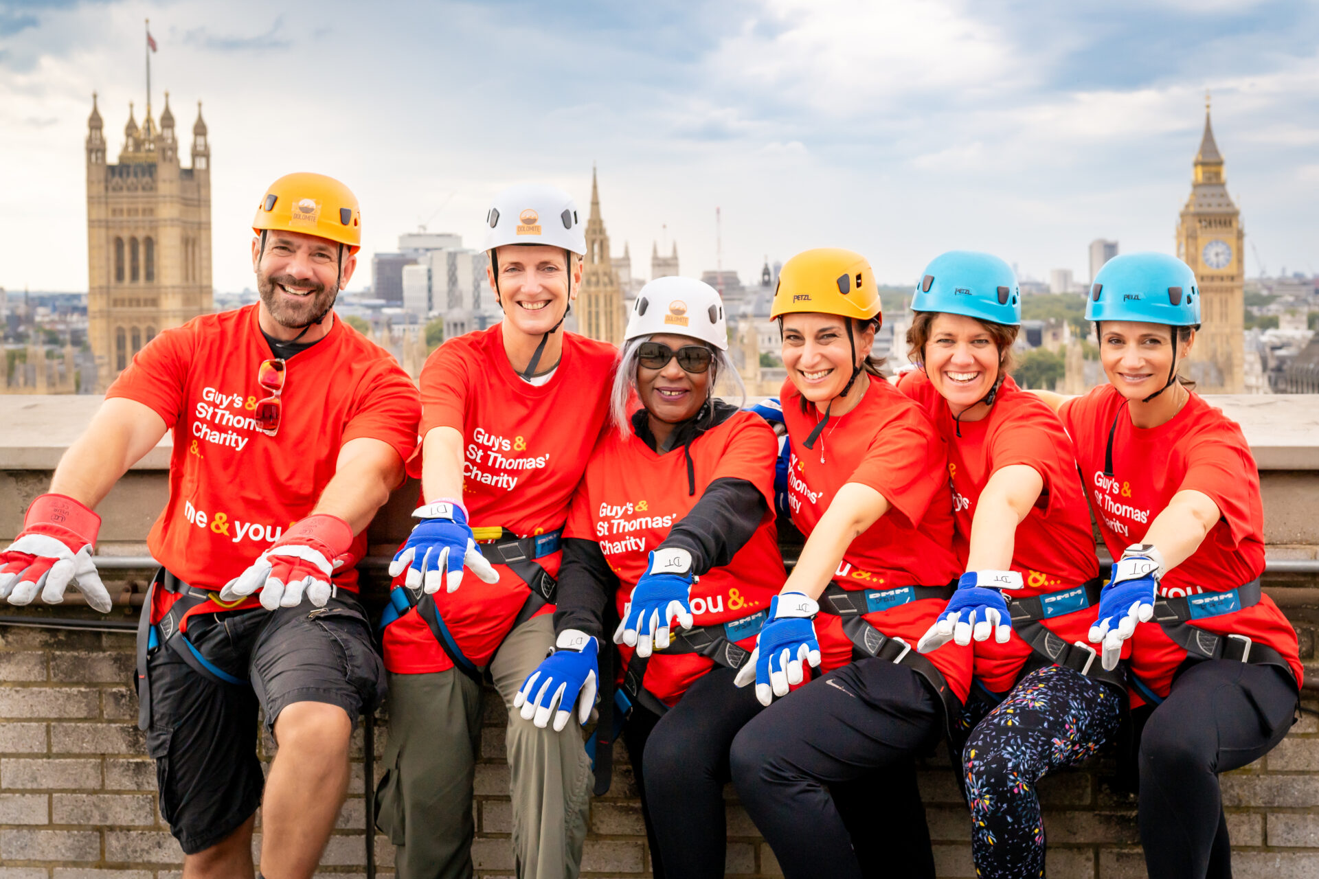 Abseilers on the roof of St Thomas hospital about to go down, with the skyline of London behind them.