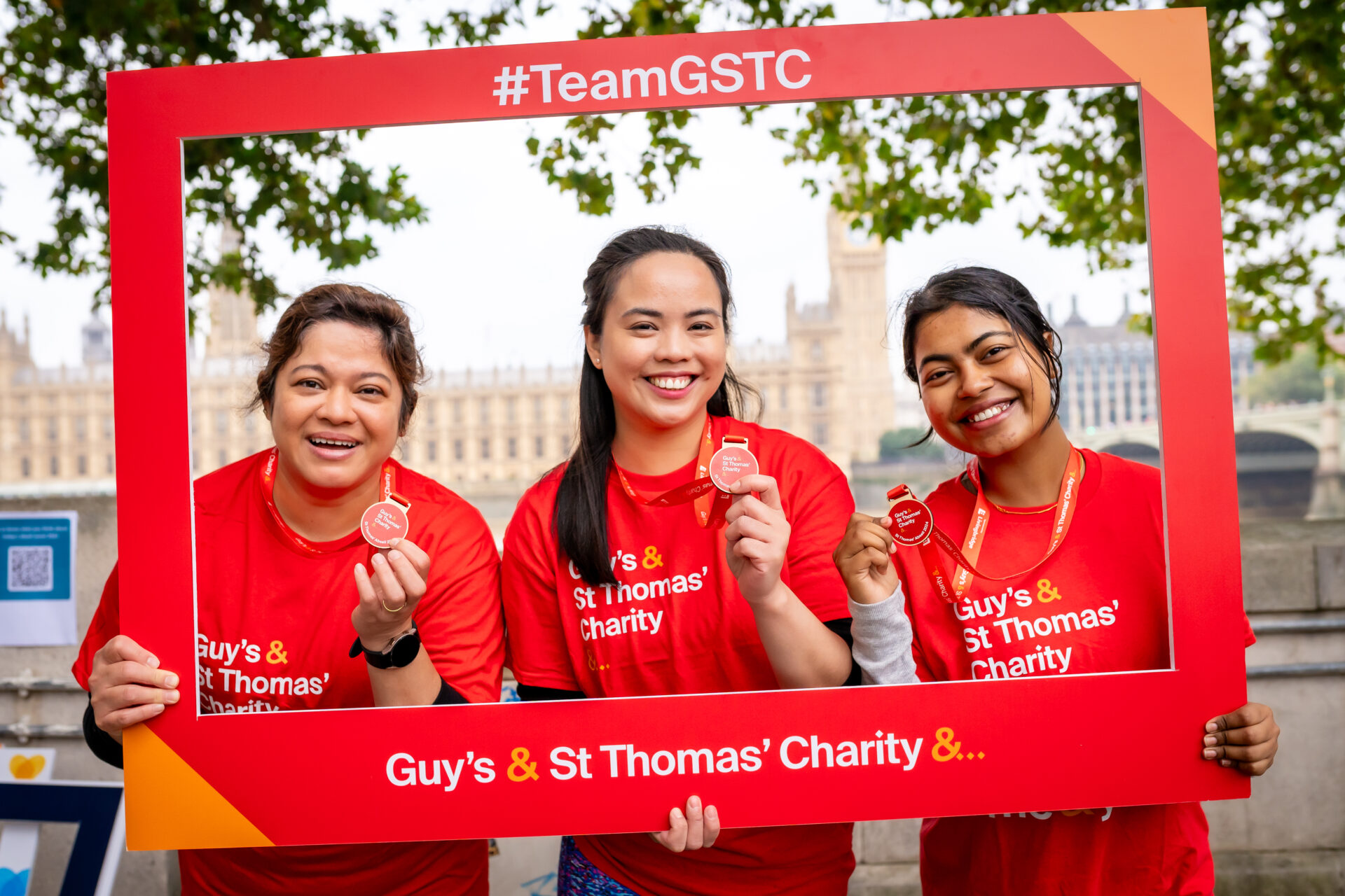Three fundraisers who had completed the St Thomas abseil challenge celebrating with their medals.