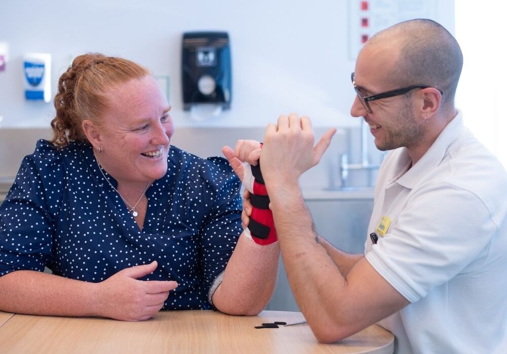 Patient Christy appears to be smiling whilst her hand is being treated by Andre on the right.