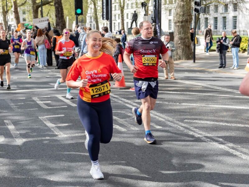 Guy's & St Thomas' Charity supporter running in a marathon, she appears to be smiling whilst running amongst participants.